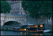 Lighted live-in barge, quay, and Pont-Neuf. Paris, France