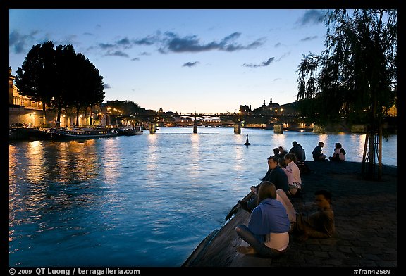 People sitting on tip of Ile de la Cite at sunset. Paris, France