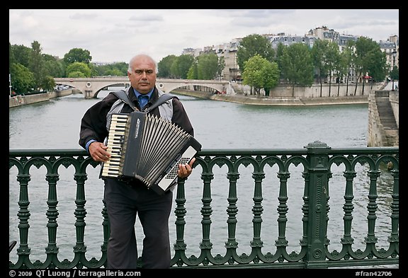 Street musician playing accordeon on River Seine bridge. Paris, France