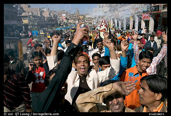 Young men celebrating and spraying wedding party in the street. Jodhpur, Rajasthan, India