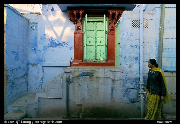 Woman walks infront of blue tinted whitewashed wall. Jodhpur, Rajasthan, India (color)