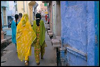 Women walking in narrow alley with blue walls. Jodhpur, Rajasthan, India