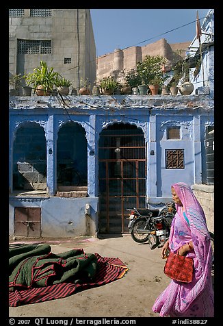 Woman in sari, blue house, and fort in the distance. Jodhpur, Rajasthan, India (color)