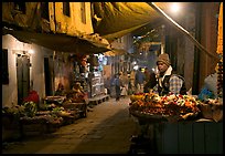 Flower vendor in  narrow old city alley at night. Varanasi, Uttar Pradesh, India ( color)