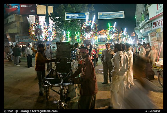 Men pulling generator on bicycle to power lights during wedding procession. Varanasi, Uttar Pradesh, India