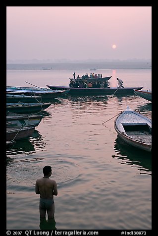 Man standing in Ganga River and boats at sunrise. Varanasi, Uttar Pradesh, India (color)