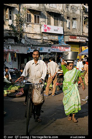 Man riding bike and woman with basket on head, Colaba Market. Mumbai, Maharashtra, India (color)