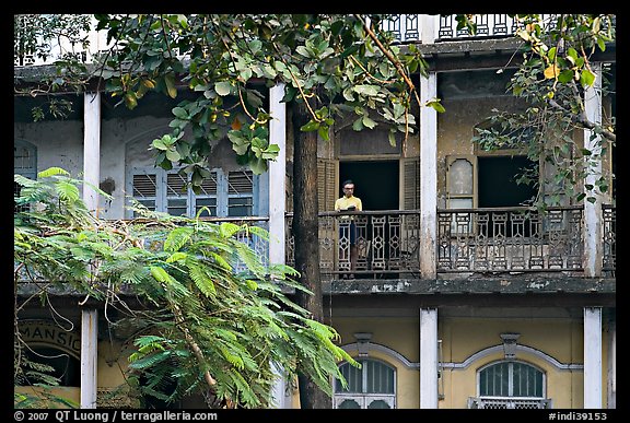 Facade with balconies and man reading. Mumbai, Maharashtra, India (color)