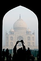 Tourist pointing  digital camera to Maj Mahal, framed by arch of gateway. Agra, Uttar Pradesh, India (color)