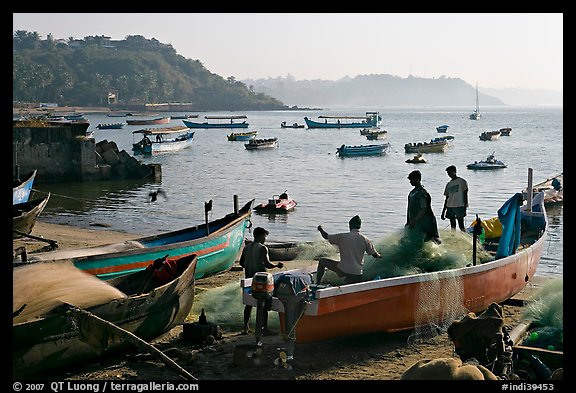 Men repairing net in small fishing boat, early morning, Dona Paula. Goa, India