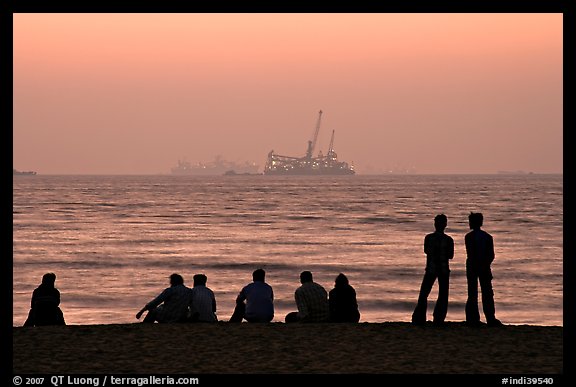 People and  off-shore platforms, Miramar Beach, sunset. Goa, India
