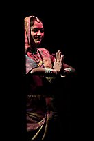 Woman joining hands in prayer gesture with dramatic lighting, Kandariya show. Khajuraho, Madhya Pradesh, India (color)