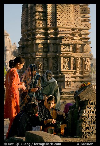 Women offering morning puja  in front temple spire. Khajuraho, Madhya Pradesh, India