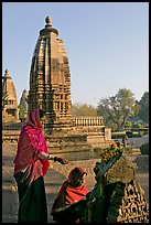 Women worshipping image with temple spire behind. Khajuraho, Madhya Pradesh, India (color)