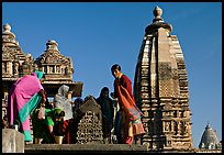 Women worshipping image with of Vahara and Lakshmana temples behind. Khajuraho, Madhya Pradesh, India