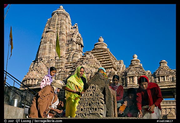 Worshippers making offering with Lakshmana temple behind. Khajuraho, Madhya Pradesh, India (color)