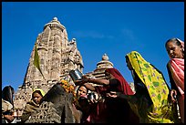 Hindu women making offerings to image with Lakshmana temple behind. Khajuraho, Madhya Pradesh, India (color)