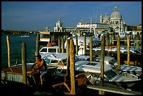 Water taxi driver cleaning out his boat in the morning, Santa Maria della Salute in the background. Venice, Veneto, Italy ( color)