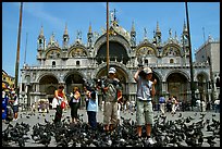 Children feeding flock of pigeon, in front of the Basilica San Marco, mid-day. Venice, Veneto, Italy (color)