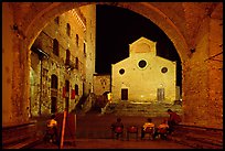 Duomo framed by an arch at night. San Gimignano, Tuscany, Italy