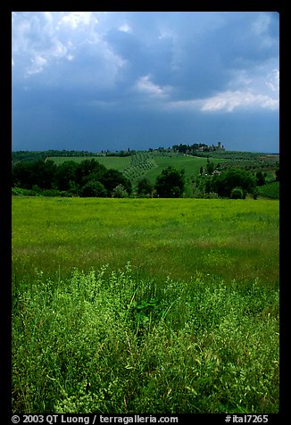 Field and distant village under storm skies. Tuscany, Italy (color)
