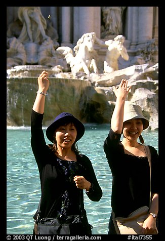 Asian tourists toss a coin over their shoulder into the Trevi Fountain. Rome, Lazio, Italy (color)