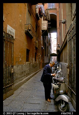 Man locking his motorbike in a side street. Naples, Campania, Italy
