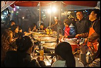 People eating noodles in a tent at night. Seoul, South Korea (color)