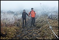 Couple hiking holding hands in fog. Jeju Island, South Korea ( color)