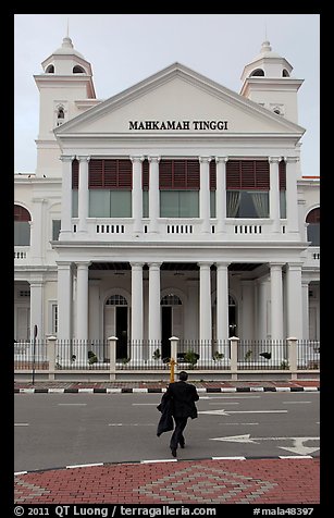 Man in suit crossing streets towards court building. George Town, Penang, Malaysia