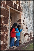 Malay girls exit on St Paul church doorway. Malacca City, Malaysia (color)