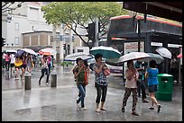 Women cross street of shopping area during shower. Singapore (color)