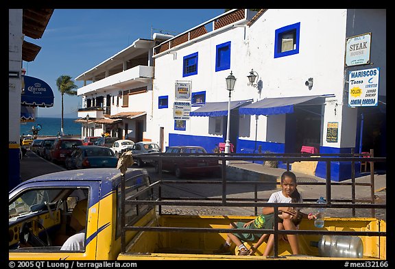 Girl riding in the back of pick-up truck in a street close to ocean, Puerto Vallarta, Jalisco. Jalisco, Mexico