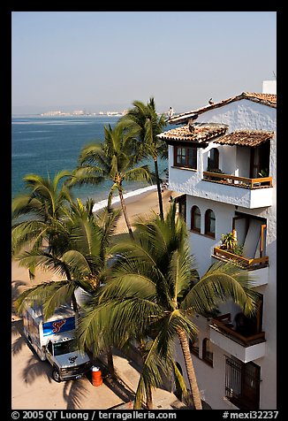 White adobe building with red tile roof,  palm trees and ocean, Puerto Vallarta, Jalisco. Jalisco, Mexico (color)
