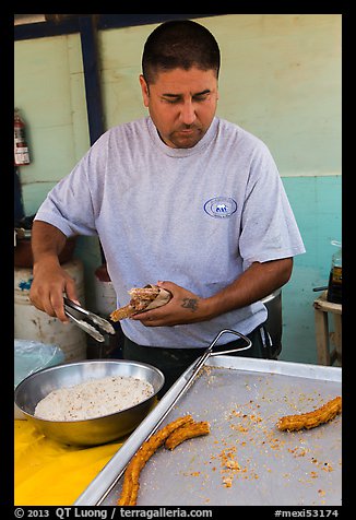 Man coating churros in sugar. Baja California, Mexico (color)
