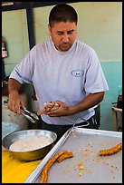 Man coating churros in sugar. Baja California, Mexico (color)