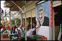 Palestinian cafe owner pointing proudly to a painting of Yasser Arafat, Jericho. West Bank, Occupied Territories (Israel) ( color)