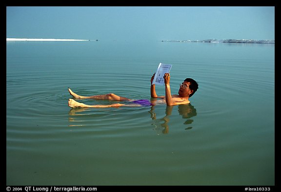Visitor reading while floating in the Dead Sea. Israel (color)