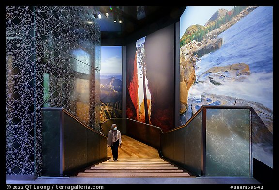 Visitor walking up stairs looking at mural prints, USA Pavilion. Expo 2020, Dubai, United Arab Emirates (color)