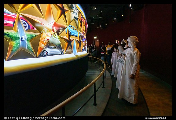 Visitors in Arab dress looking at curved wall of stars with projected media, USA Pavilion. Expo 2020, Dubai, United Arab Emirates (color)