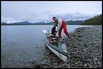 Kayaker loading gear into a double kayak. Glacier Bay National Park, Alaska ( color)