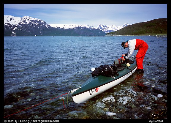 Kayaker tying up gear on top of the kayak,  East Arm. Glacier Bay National Park, Alaska