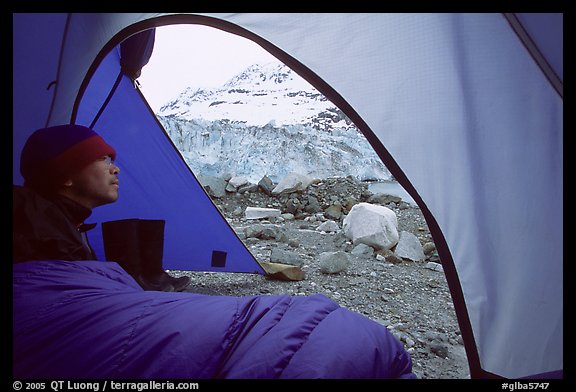 Camper lying in sleeping bag looks at Lamplugh Glacier. Glacier Bay National Park, Alaska (color)