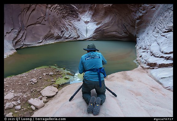 Photographer kneeling with tripod at a narrow slot canyon pool, North Canyon. Grand Canyon National Park, Arizona (color)