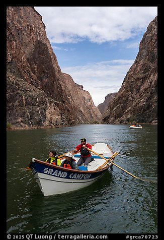 Dory boat labeled Grand Canyon carrying passengers on the Colorado River between Granite Gorge high canyon walls. Grand Canyon National Park, Arizona (color)