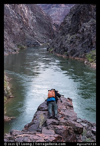 Photographer lying prone with camera over a cliff edge above the Colorado River at Ninetyone mile. Grand Canyon National Park, Arizona (color)