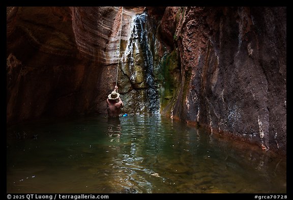 Man rappelling into a pool beside a narrow waterfall in Blacktail Canyon. Grand Canyon National Park, Arizona (color)