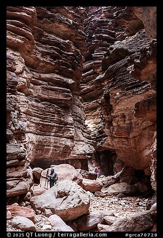 Photographers exploring the Blacktail deep slot canyon with layered red rock walls. Grand Canyon National Park, Arizona (color)