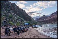 Group of river rafters seated on a sandy beach having dinner near their camp on the Colorado River. Grand Canyon National Park, Arizona ( color)