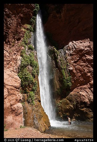 Person standing under the Deer Creek tall desert waterfall in a red rock canyon. Grand Canyon National Park, Arizona (color)